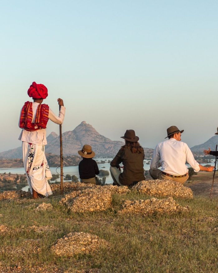 Guide en habit traditionnel du Rajasthan et voyageurs observant un paysage de lacs et collines